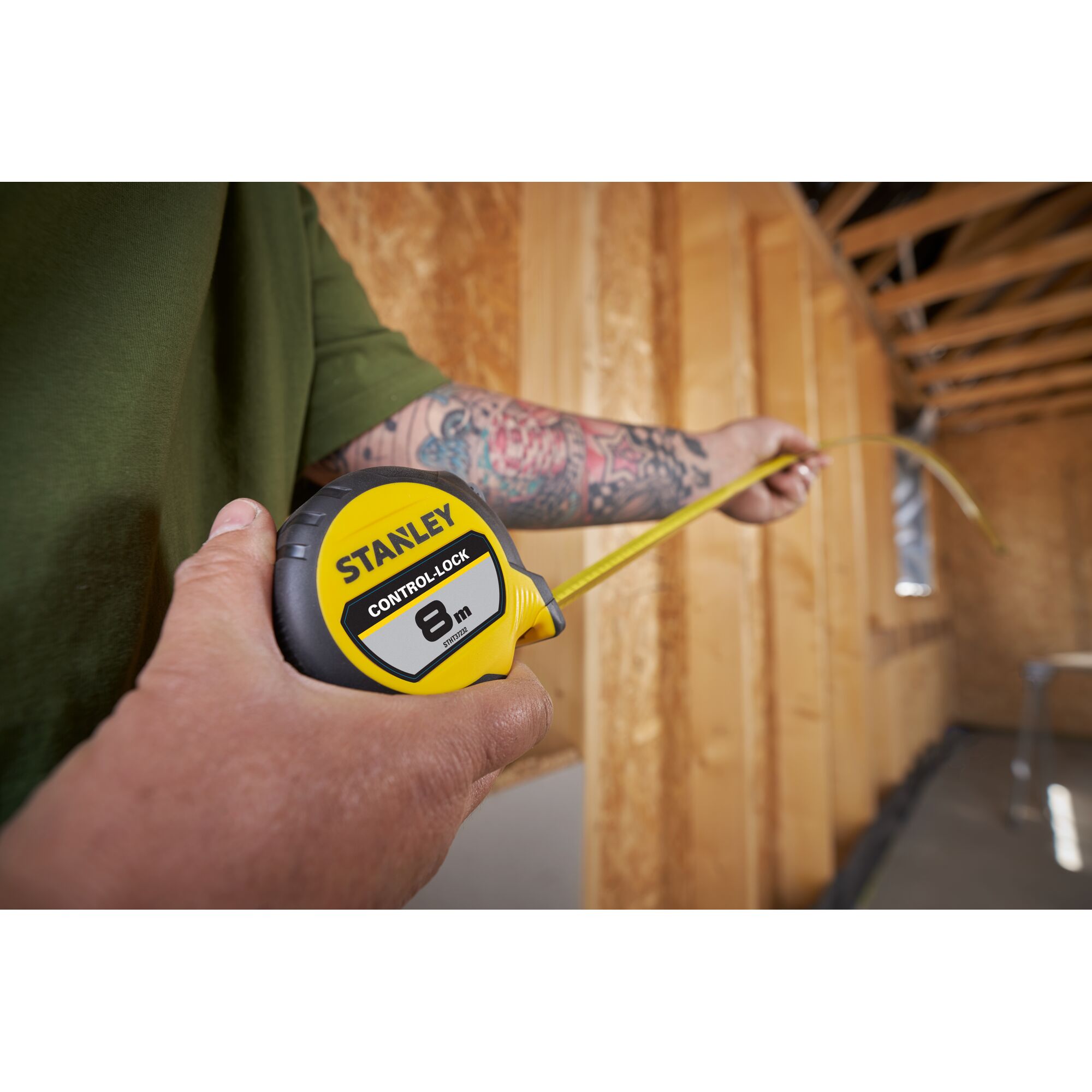 Photo of STANLEY STHT37232 8m tape measure in use, yellow and black design, person measuring wooden construction.